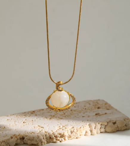 Collar con dije de planeta con circonias. Color dorado.